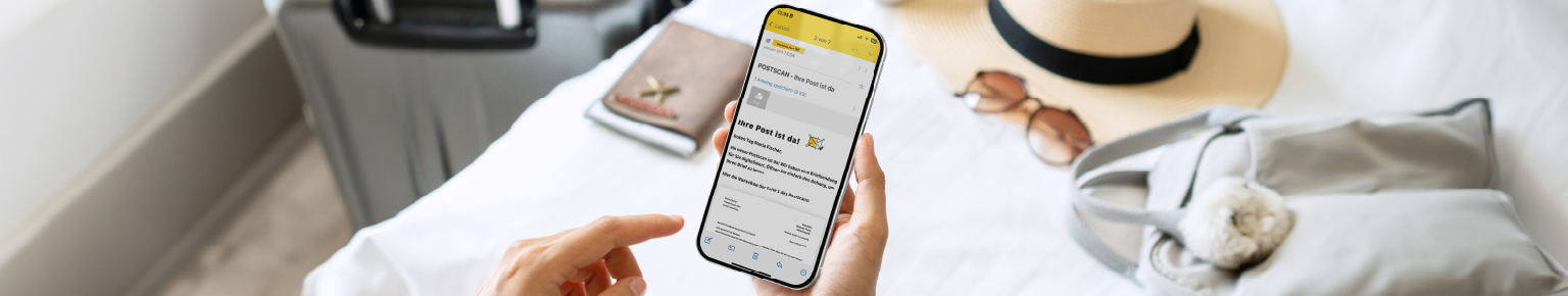 Handy mit Postscan Nachricht im Vordergrund, Reiseutensilien im Hintergrund