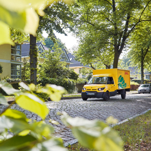 Zustellfahrzeug mit Logo GoGreen Plus f�hrt in Wohnallee entlang